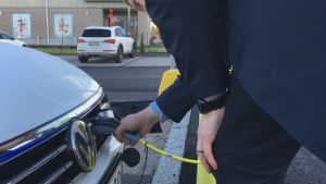 Frågorna kring elbilar är många bland tyska kunder. En man sätter sladden in i en elbil som ska laddas.