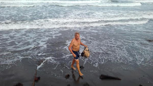 Simo Aaltonen kävelee rannalla ja kerää roskaa