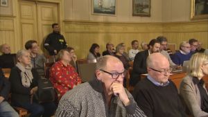 Väktare fanns på plats i fullmäktigesalen i Kaskö då frågan om fusion med Närpes avgjordes i december 2019. Fullmäktigeledamoter på möte, i bakgrunden en väktare.