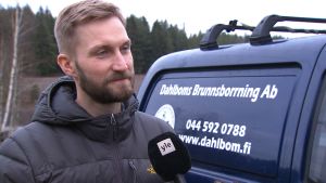Kristian Dahlbom jobbar med att bygga brunnar. Kristian Dahlbom, en man med skägg och mustasch, står farmför en blå bil med texten Dahlboms brunnsborrning.