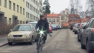 Jonas cyklar varje dag till jobbet på Folkhälsanhuset i Brunakärr. En man cyklar längs med en väg och signalerar sväng till vänster med handen.