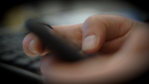 Flera finländska mobilspelsföretag använder sig av lootlådor. Händer som håller i en mobiltelefon. Fotograferat från sidan.