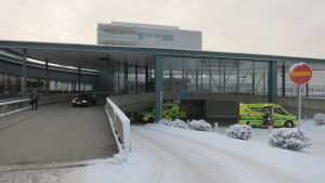 Entrén till centralsjukhuset i Rovaniemi. Utanför står två ambulanser. Det ligger snö på marken.
