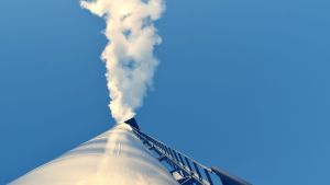 Fjärrvärme blir ett allt grönare alternativ. En skorsten som sträcker sig högt upp i luften, ut kommer vit rök, förmodligen vattenkondens.
