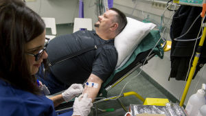 "Det finns många som säger att man måste göra något åt psykisk ohälsa. Varför kan inte det vara det här, ifall människor har nytta av det?" Man får vätska intravenöst genom venkateter. Sjuksköterska håller nålen på plats.