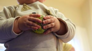 Många föräldrar kan uppleva babytiden som fängslande, både i positiv och negativ bemärkelse. Två babyhänder som håller i en boll.