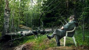 Rainer Rajakallio on valinnut elämän erakkona. Mies istuu muovituolilla keskellä metsää.