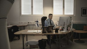Kriminalkommissarie Mats Sjöholm. Polis som sitter vid ett skrivbord framför en dator.