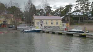 Restaurang Rantamakasiini i Merimasku. En gul restaurangbyggnad med en lång brygga där några båtar ligger.