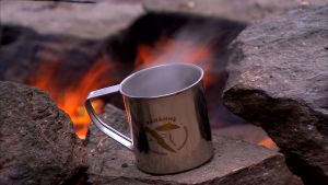 Kahvitauko Kelventeen saarella Päijänteen kansallispuistossa. En kaffemugg av plåt vid en eldstad av sten.