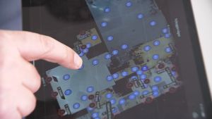 Bilderna görs till en 3D-modellering av fastigheten. Ett pekfinger rör vid en pekdator, där en karta med siffror visar hur en fastighets plan ser ut