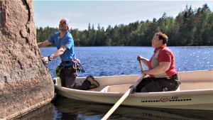 Olhavanvuoren kalliomaalaus on 6 000 vuotta vanha. Timo Toivanen och ELisabeth Morney sitter i en roddbår och tittar på en hällmålning vid Olhavanvuori.