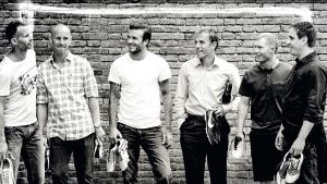 Manchester United -pelaajat David Beckham, Nicky Butt, Ryan Giggs, Paul Scholes, Phil ja Gary Neville vierekkäin tiiliseinän edessä nappiksen käsissään mustavalkoisessa kuvassa.