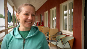 Tatiana Vuhliar är nöjd på Keskylä gård, men hon känner till gårdar där förhållandena inte är så bra. Tatiana Vuhliar, en dam med ljusgrön munkjacka, står på verandan till ett hus.