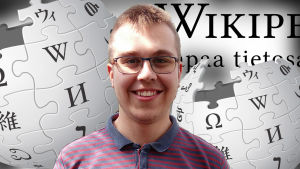 Tuomas Ahola katsoo kameraan ja taustalla Wikipedian logo
