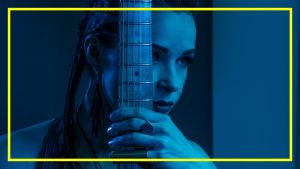 Erja Lyytinen poseeraa kitaran kanssa. Kuvan valo on sininen.