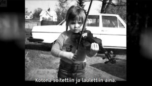 Kuvakaappaus televisio-ohjelmasta Daniel Olinin vieraana kapellimestari Anna-Maria Helsing: kuvassa Helsing soittaa viulua pikkutyttönä.