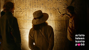 Ihmiset tutkivat hieroglyjejä luolassa.