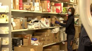 Postombudens hyllor är fyllda med paket. Här sorterar Jenni Kiviniemi paket i Kristinestad. En kvinna sorterar paket. Hyllorna är fulla av paket.