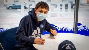 För en tid sedan skrev Kai Meriluoto på kontraktet som gäller för tre säsonger i ligalaget HJK. En person skriver sitt namn på ett papper.