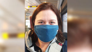 Kapellimestari Anna-Maria Helsing lentokenttäjunassa maski kasvoilla.