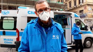 Läkaren Andrea Carrozzini och tolken Ousmane Toure (i bakgrunden) finns vid tågstationen Termini med den ambulerande kliniken en gång i veckan. En man står framför en vit skåpbil med texten rörlig klinik.
