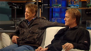 Martti ja Mikko Syrjä istuvat valkoisella sohvalla Arto Nybergin haastattelussa vuonna 2004.
