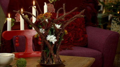 Ett blomsterarrangemang av blåbärsris och snittblommor på bordet i salen i Strömsö.