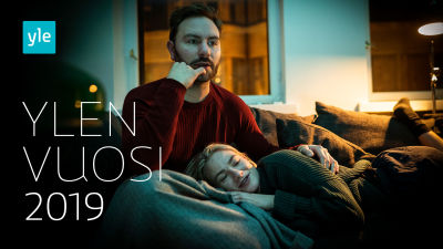 Nainen ja mies katselevat televisiota sohvalla. Kuvassa teksti Ylen vuosi 2019.