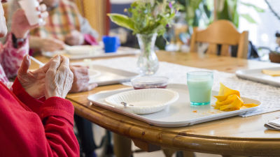 Matbord med använda kärl. Äldre personer sitter runt bordet.