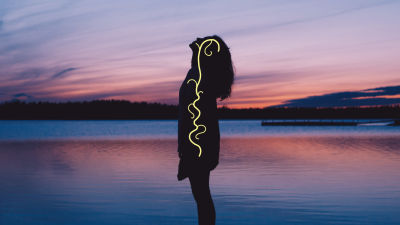 Nainen seisoo rannalla siluettina. Hänen kehossaan kulkee vagus-hermo keltaisena juosteena.