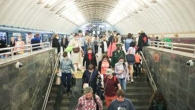 Människor går ner för trappan i S:t Petersburgs metro. De flesta bär munskydd.