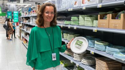 Nora Lehtinen visar upp engångstallrikar vid en butikshylla.