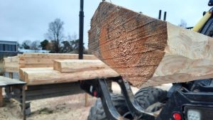 Varje år används cirka sju miljarder euro på offentliga byggprojekt i Finland vilket gör ett ökat träbyggande till ett effektivt sätt att nå energi- och klimatmålen. stock som sticker ut på släpet av en skogsmaskin.