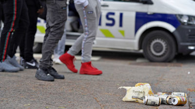 Ölburkar som ligger på marken framför ungdomar.