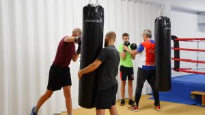 Salen fylls av ljudet av boxningshandskar mot boxningssäckar. Boxningsträning