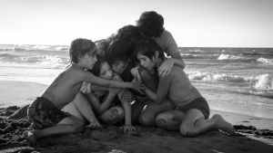 Lapset ja lastenhoitaja halaavat toisiaan meren rannalla. Kuva Alfonso Cuarónin elokuvasta Roma (2018).
