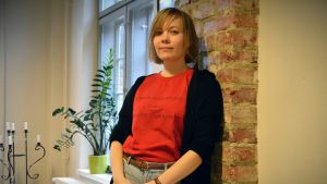 Ylva Perera säger att det faller sig naturligt att konstnärer reagerar kraftigt på fascistiska krafter. Ylva Perera, i en röd t-shirt, lutar sig mot en tegelvägg.