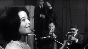 Tuokiokuva ohjelmasta "Carola – pieni palapeli" vuodelta 1966. Carola Standertskjöld laulaa Esa Pethmanin orkesterin solistina.
