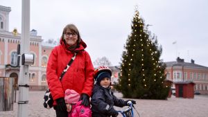 Ulla Lindström tycker att snö på gatorna skulle lyfta fram julbelysningen ännu mera. Ulla Lindström med hennes barnbarn.