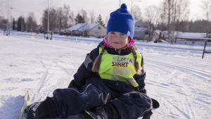 Lotta Koro lärde sig skida redan som 3-åring Lotta Koro har skidor på och sitter på marken.