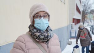 Christine Huusko har kommit till församlingshemmet från Kråkö. Christine Huusko framför en gul vägg med munskydd på.
