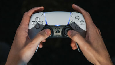 Playstation 5 pelikonsolin ohjain pelaajan käsissä.