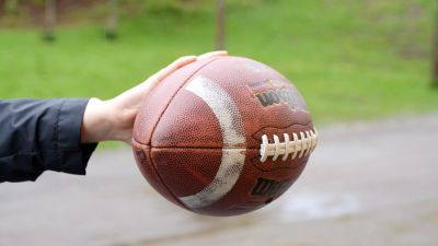 Hand som håller i en amerikansk fotboll.