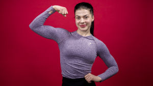 Fitnessurheilija ja suosittu tubettaja Pernilla Böckerman esittelee hauistaan kameralle punaista taustaa vasten.