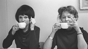 Kaksi naista tupakoi ja juo kahvia.