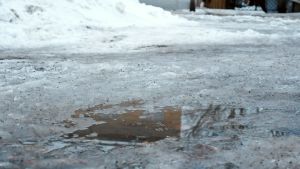 Det varma vädret förvandlar isen på utomhusplanerna till snöslask. Vattenpöl och snöslask.