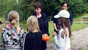 Malin Vesalainen och Gunvor Karlsson-Lindholm är bekant med skolbarnen sedan tidigare. Gunvor Karlsson-Lindholm och Malin Vesalainen talar med några skolbarn som hittat en lunchlåda i skogen.