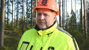 Skogsbolaget som Kristian Blomqvist jobbar i har försökt fördela arbetena rättvist så alla ska få någon inkomst. Kristian Blomqvist står i skogen iklädd skyddshjälm och reflexväst.