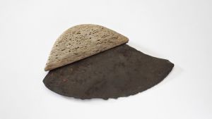 Kvinnokniv eller "ulu" från Alaska. Kvinnorna bearbetade läder och skar kött och fisk med denna kniv. Eggen består av den metamorfa bergarten glimmerskiffer och skaftet av ben. Så kallad kvinnokniv med halvcirkelformad egg av den metamorfa bergarten glimmerskiffer och ett skaft av trä.